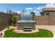 A backyard hot tub sits on pavers in a tranquil setting with privacy walls and a small green lawn at 16756 S 181St Ln, Goodyear, AZ 85338