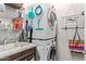 Functional laundry room with stacked washer/dryer, sink, storage shelves, and decorative touches at 16756 S 181St Ln, Goodyear, AZ 85338