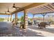 Inviting covered patio with ceiling fans, comfortable seating, and views of the well-maintained backyard and swimming pool at 18121 E San Luis Dr, Gold Canyon, AZ 85118