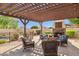 Relaxing outdoor living space with a cozy fireplace and comfortable seating under a stylish pergola at 18121 E San Luis Dr, Gold Canyon, AZ 85118