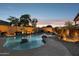 An outdoor pool with rock features, lighting, and mature trees offers a relaxing backyard space at 18121 E San Luis Dr, Gold Canyon, AZ 85118