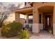 Covered front porch with seating area, tiled floor, desert landscaping, and decorative front door at 18121 E San Luis Dr, Gold Canyon, AZ 85118