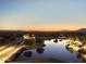 Scenic aerial view of a tranquil lake at dusk, reflecting the lights of the surrounding community at 19182 N Smith Dr, Maricopa, AZ 85139