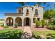 Charming two-story home featuring a stucco facade, arched entryways, and a well-manicured front yard with lush landscaping at 20409 W Thayer St, Buckeye, AZ 85396
