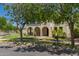 Charming two-story home with arched entryways, mature trees, and a well-maintained lawn, presenting a picturesque suburban setting at 20409 W Thayer St, Buckeye, AZ 85396