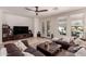 Inviting living room with a plush brown sectional sofa, ceiling fan, and view to the outdoor pool area at 20409 W Thayer St, Buckeye, AZ 85396