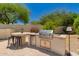 Outdoor kitchen with stainless steel grill, mini fridge, and bar seating at 20409 W Thayer St, Buckeye, AZ 85396