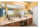 Well-lit bathroom features tile flooring, double sinks with wood cabinets, and a large mirror at 2124 W Harwell Rd, Phoenix, AZ 85041