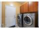 Laundry room features tile flooring, wood cabinets, and a washer and dryer at 2124 W Harwell Rd, Phoenix, AZ 85041