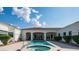 An in-ground pool and jacuzzi with tile deck, and the back of the white-exterior house with arched doorways and windows at 3126 E Fruitvale Ct, Gilbert, AZ 85297