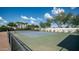 Full view of the tennis court, complete with net, fence, mature trees, and landscaping at 3126 E Fruitvale Ct, Gilbert, AZ 85297