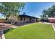 Large backyard featuring manicured turf, covered patio, firepit, and mature trees at 3251 W Mercer Ln, Phoenix, AZ 85029