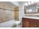 Bathroom featuring a wooden vanity, shower/tub combo with tan tiling, decorative mirror, and updated fixtures at 3251 W Mercer Ln, Phoenix, AZ 85029
