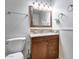Bathroom featuring a wooden vanity, white sink and toilet, decorative mirror, and updated fixtures at 3251 W Mercer Ln, Phoenix, AZ 85029