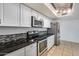 Updated kitchen with stainless steel appliances, white cabinets, tile backsplash, and dark granite countertops at 3251 W Mercer Ln, Phoenix, AZ 85029
