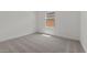 An empty bedroom with neutral carpet, white walls, baseboards, and a bright window at 42510 W Peters Dr, Maricopa, AZ 85138