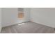 An empty bedroom with neutral carpet, white walls, baseboards, and a bright window at 42510 W Peters Dr, Maricopa, AZ 85138