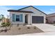 Charming home featuring a two-car garage, desert landscaping, and eye-catching blue shutters on the front window at 42510 W Peters Dr, Maricopa, AZ 85138