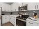 Close up of a kitchen area featuring stainless appliances, white cabinets, gray backsplash and wood flooring at 475 N 9Th St # 206, Phoenix, AZ 85006