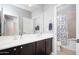 Bathroom featuring double sinks, a wide mirror, and a shower with a stylish shower curtain at 5208 W Straight Arrow Ln, Phoenix, AZ 85083