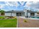 Backyard with grass, desert landscaping, patio, and modern home on a sunny day at 5937 E Corrine Dr, Scottsdale, AZ 85254