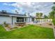 Backyard with lush green grass, patio, desert landscaping, and modern home under blue sky at 5937 E Corrine Dr, Scottsdale, AZ 85254