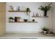 Kitchen counter with floating shelves displays decorative items, plants, and cookbooks at 5937 E Corrine Dr, Scottsdale, AZ 85254