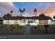 Modern home exterior with desert landscaping, a walkway, and palm trees during sunset at 5937 E Corrine Dr, Scottsdale, AZ 85254