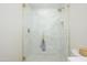 Clean, bright walk-in shower with white tile, gold accents, and a glass door at 5937 E Corrine Dr, Scottsdale, AZ 85254