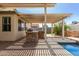 Covered patio featuring an outdoor kitchen with a stone base and built-in grill overlooking the in-ground pool at 8256 W Bloomfield Rd, Peoria, AZ 85381