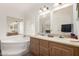 Bright bathroom features a tub under a window, double sink vanity with cabinets and wall to wall mirror at 8832 E Pueblo Ave # 71, Mesa, AZ 85208