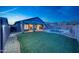 Nighttime view of the fenced backyard with artificial turf and a sparkling pool at 10253 E Indigo Dr, Scottsdale, AZ 85255