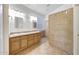 Tile bathroom featuring double sinks, a large mirror, decorative lighting, and a tiled shower at 10253 E Indigo Dr, Scottsdale, AZ 85255