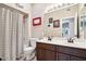 Well-lit bathroom featuring a double sink vanity with dark wood cabinets and a shower with a striped curtain at 11861 E Becker Ln, Scottsdale, AZ 85259