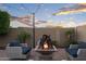 Backyard featuring a fire pit surrounded by seating under string lights and a colorful sunset at 12152 W Briles Rd, Peoria, AZ 85383