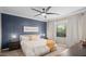 Serene bedroom with a ceiling fan, blue accent wall, and ample natural light at 12152 W Briles Rd, Peoria, AZ 85383