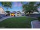 Lush green backyard with manicured lawn, mature trees, covered patio and neutral-colored stucco home at 13295 N 153Rd Ln, Surprise, AZ 85379