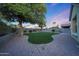 Large backyard showcasing a green lawn, mature trees, and a rock perimeter, with a block wall fence for privacy at 13295 N 153Rd Ln, Surprise, AZ 85379