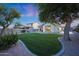 Spacious backyard with mature trees, green lawn, gravel and privacy fencing under a twilight sky at 13295 N 153Rd Ln, Surprise, AZ 85379