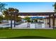 Outdoor kitchen with stainless steel grill, and a pergola with lights near a pool and putting green at 13620 N 80Th Pl, Scottsdale, AZ 85260
