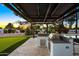 Outdoor stainless steel grill under a lighted pergola, next to a putting green at 13620 N 80Th Pl, Scottsdale, AZ 85260