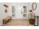Bright entryway featuring a white door, wood-look floors, bench, and decorative mirror at 13620 N 80Th Pl, Scottsdale, AZ 85260