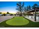 Backyard with a putting green and an outdoor kitchen and bar under a pergola at 13620 N 80Th Pl, Scottsdale, AZ 85260