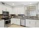 Modern kitchen with stainless steel appliances, gray counters, diamond pattern backsplash, and decorative glass block window at 17850 N 68Th St # 2138, Phoenix, AZ 85054