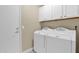 Bright laundry room with white washer and dryer and upper cabinets for storage at 19107 N 94Th Ave, Peoria, AZ 85382