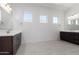 Bathroom featuring dark wood vanities, double sinks, modern fixtures, and bright lighting at 20256 W Monterey Way, Buckeye, AZ 85396