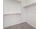 Walk-in closet with carpet and multiple white shelves and wooden hanger rods for storage and organization at 20256 W Monterey Way, Buckeye, AZ 85396