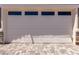A clean, white garage door with four small windows and a nicely patterned driveway at 20256 W Monterey Way, Buckeye, AZ 85396