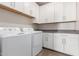 Laundry room features white washer and dryer, white shaker cabinets, and gray countertops at 20783 W Pasadena Ave, Buckeye, AZ 85396