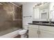 Bathroom featuring a shower-tub combo with glass door and modern vanity with a dark countertop at 3644 W Maryland Ave, Phoenix, AZ 85019